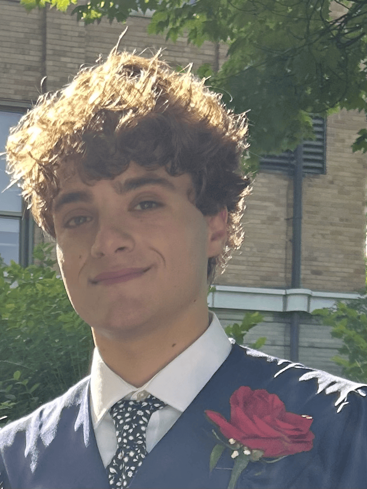 head shot of Theo wearing a blue suit with a boutonniere
