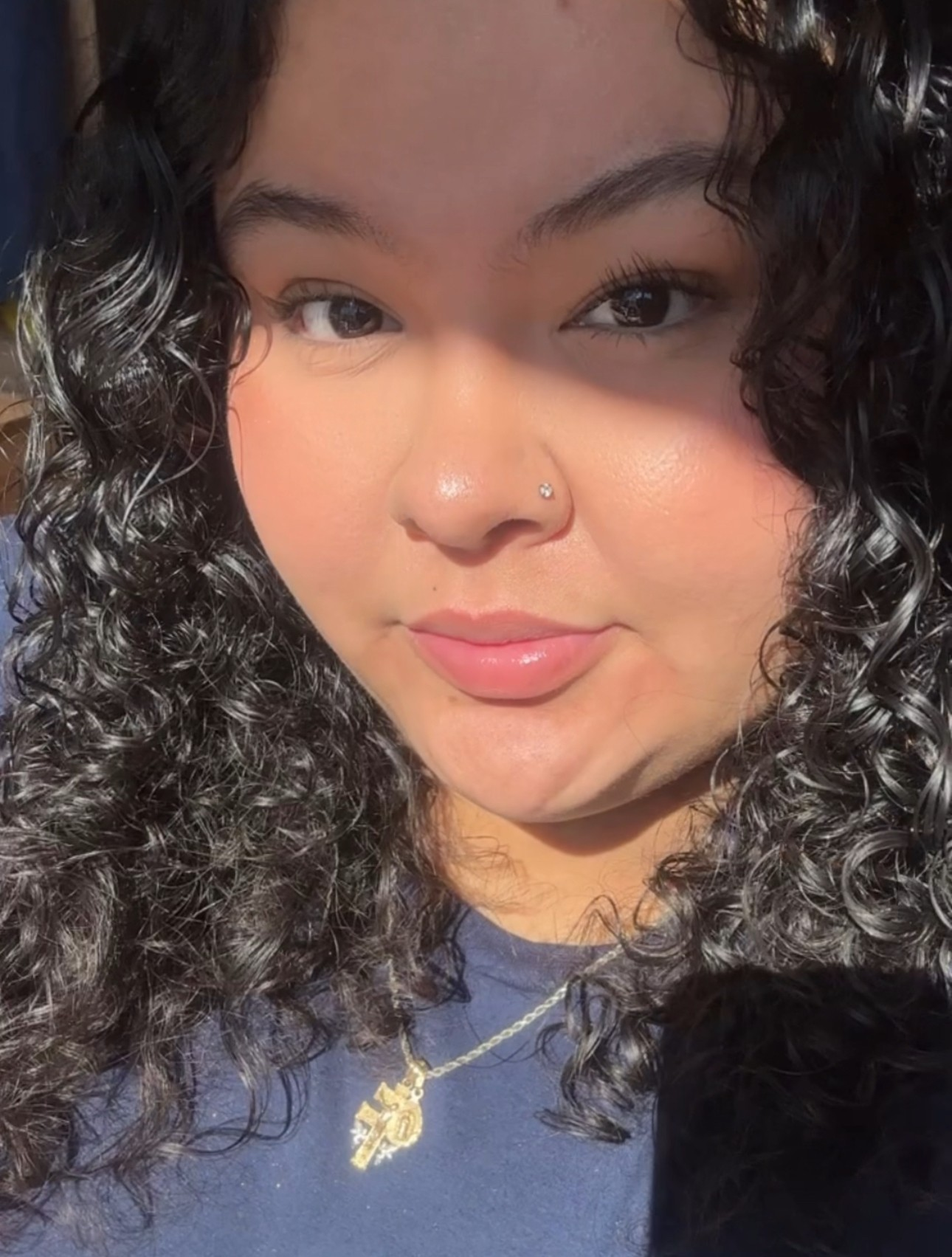 Selfie of Iris wearing a blue shirt with a gold necklace